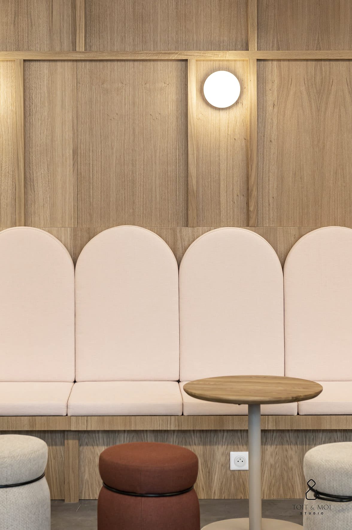 Banquette à dossiers arrondis devant un mur en panneaux de bois